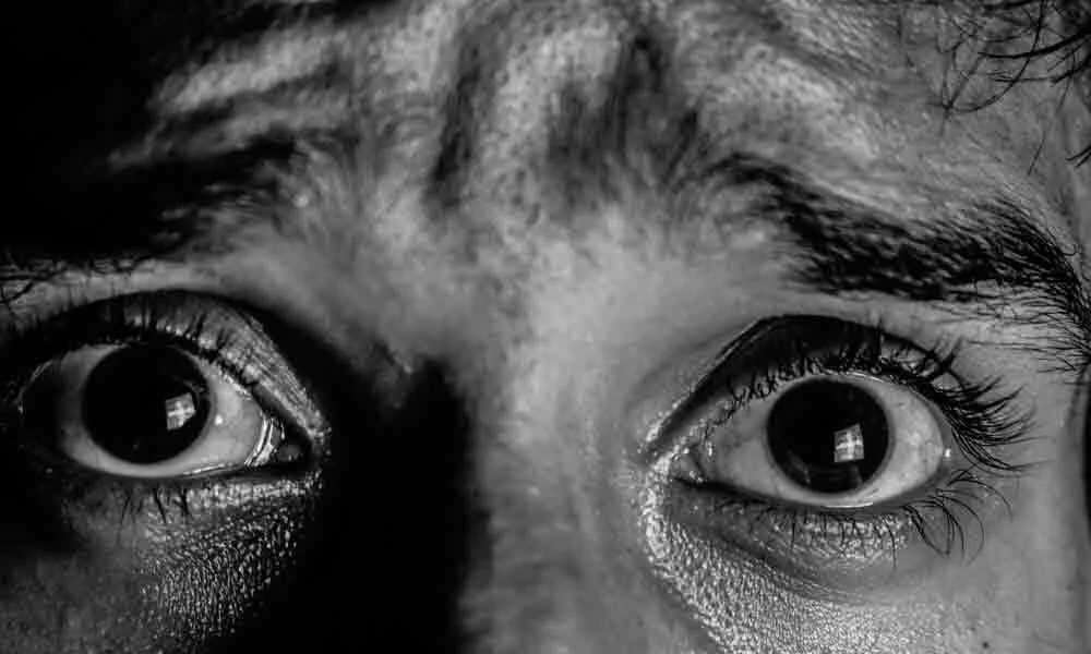 Primerísimo plano en blanco y negro de dos ojos muy abiertos con expresión de miedo o terror.