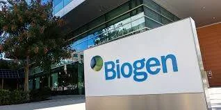 Cartel con el logo de Biogen frente a un edificio corporativo moderno rodeado de vegetación.