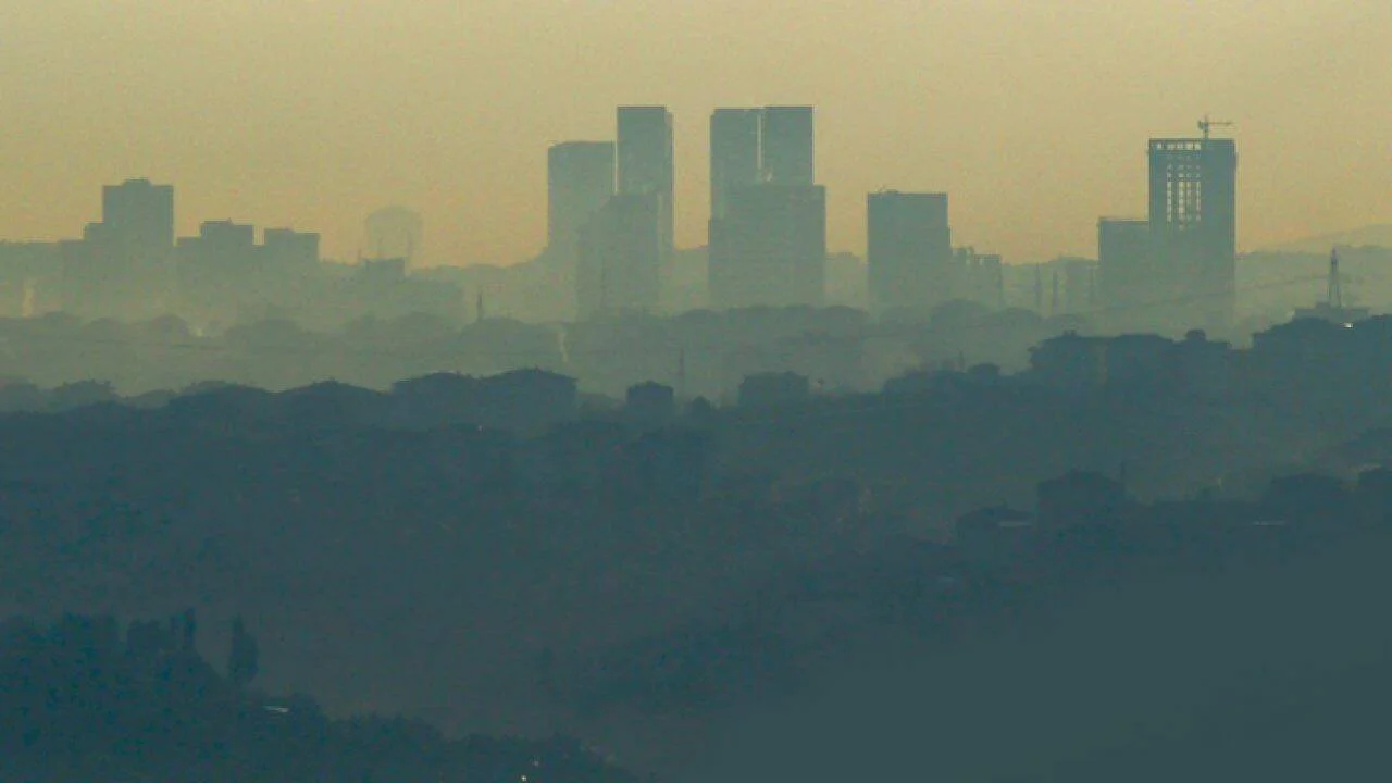 Horizonte de una ciudad envuelto en una densa capa de smog que difumina los rascacielos bajo un cielo amarillento.