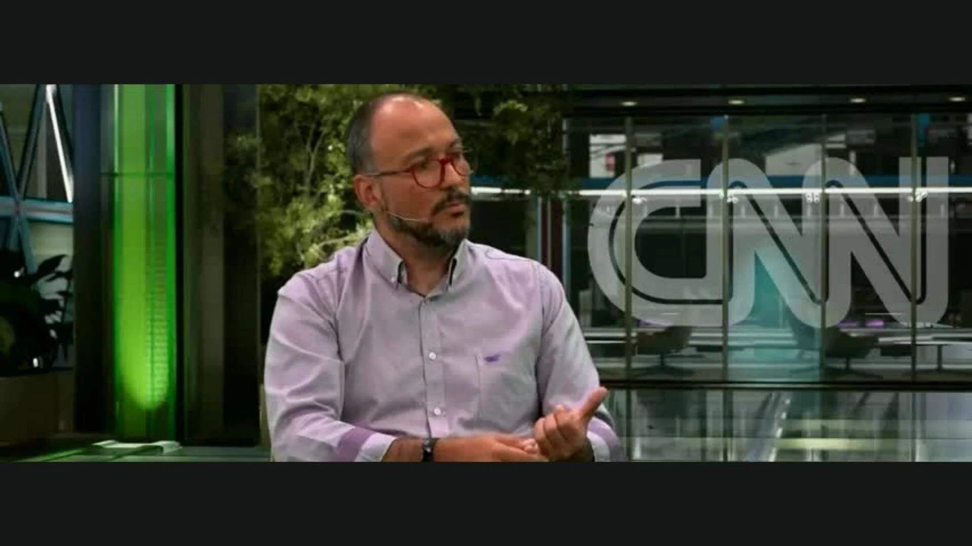 Hombre con anteojos rojos y barba habla gesticulando en un estudio de televisión de CNN.
