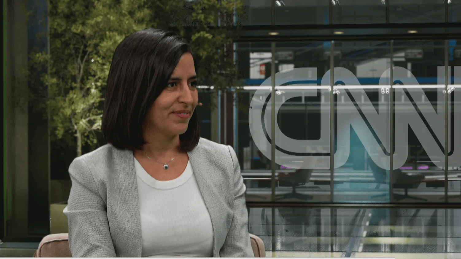 Mujer de cabello oscuro con saco gris sentada frente al logo de CNN durante una entrevista en estudio.
