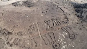 Vista aérea de geoglifos y estructuras funerarias antiguas trazadas sobre un terreno desértico árido.