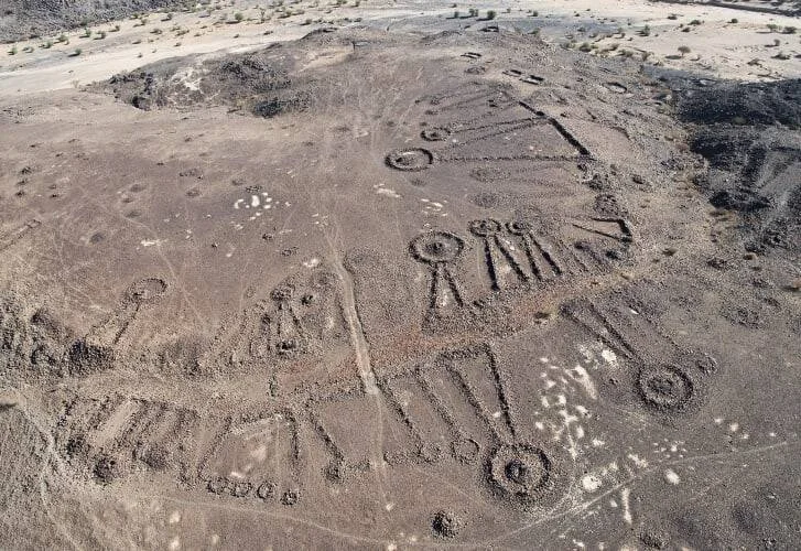 Vista aérea de geoglifos y estructuras funerarias antiguas trazadas sobre un terreno desértico árido.