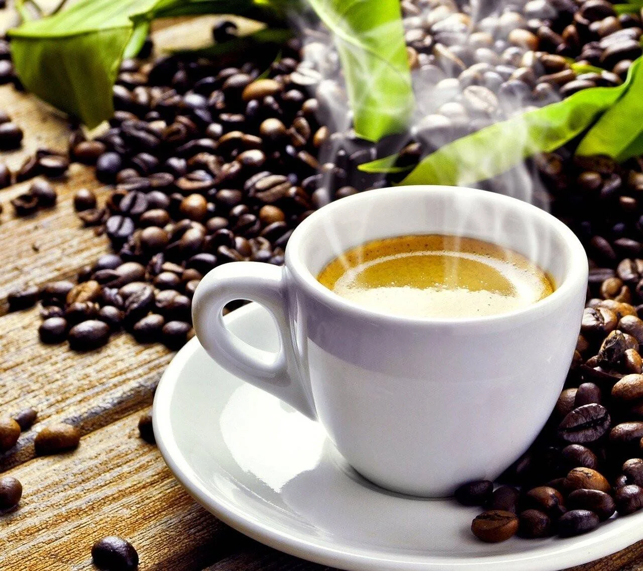 Taza blanca de espresso recién preparado con vapor, rodeada de granos de café tostado sobre una mesa de madera.