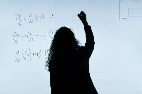 Silueta de una persona escribiendo ecuaciones matemáticas en una pizarra blanca.