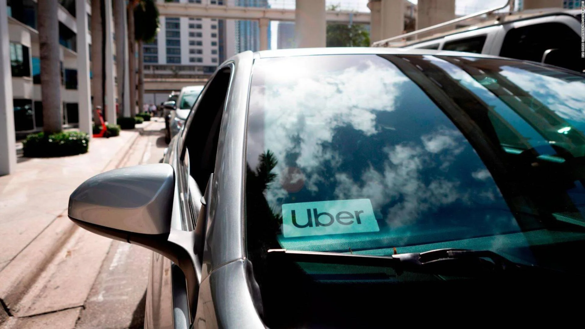 Auto estacionado en zona urbana con el logo de Uber pegado en el parabrisas delantero.