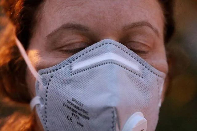 Mujer con los ojos cerrados usando una mascarilla de protección respiratoria FFP2.