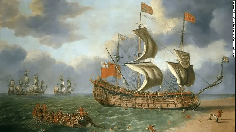 Óleo histórico que muestra un gran navío de guerra británico con velas desplegadas y banderas inglesas, acompañado de embarcaciones menores en la costa.