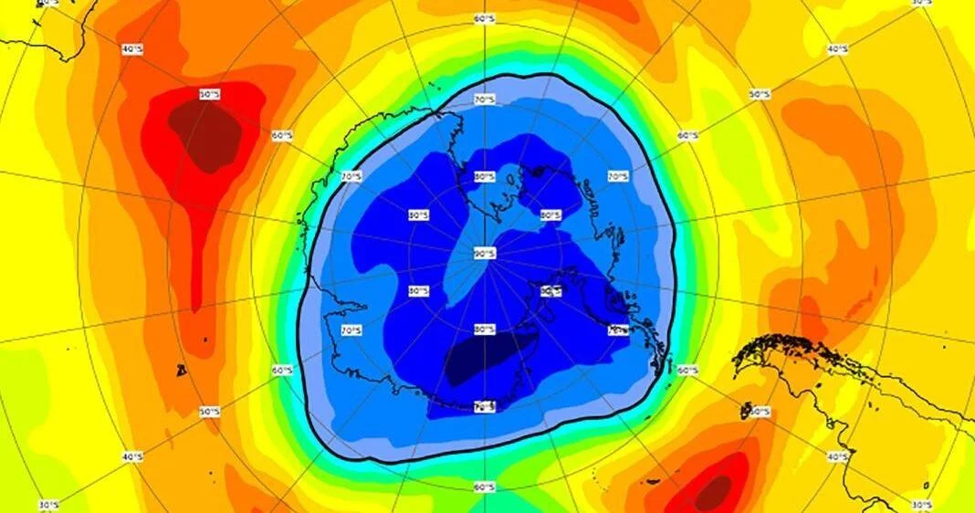 Mapa satelital que muestra el agujero en la capa de ozono sobre la Antártida, con tonos azules en el centro indicando baja concentración de ozono.