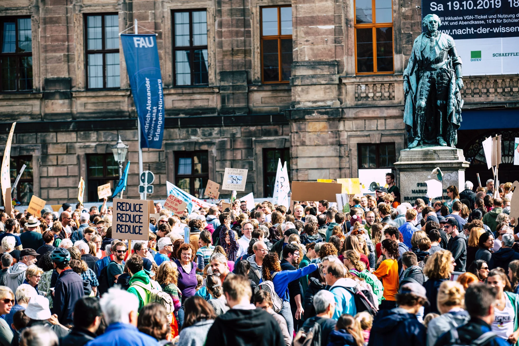 Multitud de manifestantes con carteles climáticos, entre ellos uno que dice 'Reduce Reduce Reduce', frente a un edificio histórico en Núremberg.