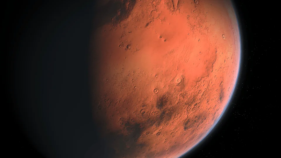 Vista del planeta Marte con su superficie rojiza y cráteres visibles, rodeado por el espacio oscuro.