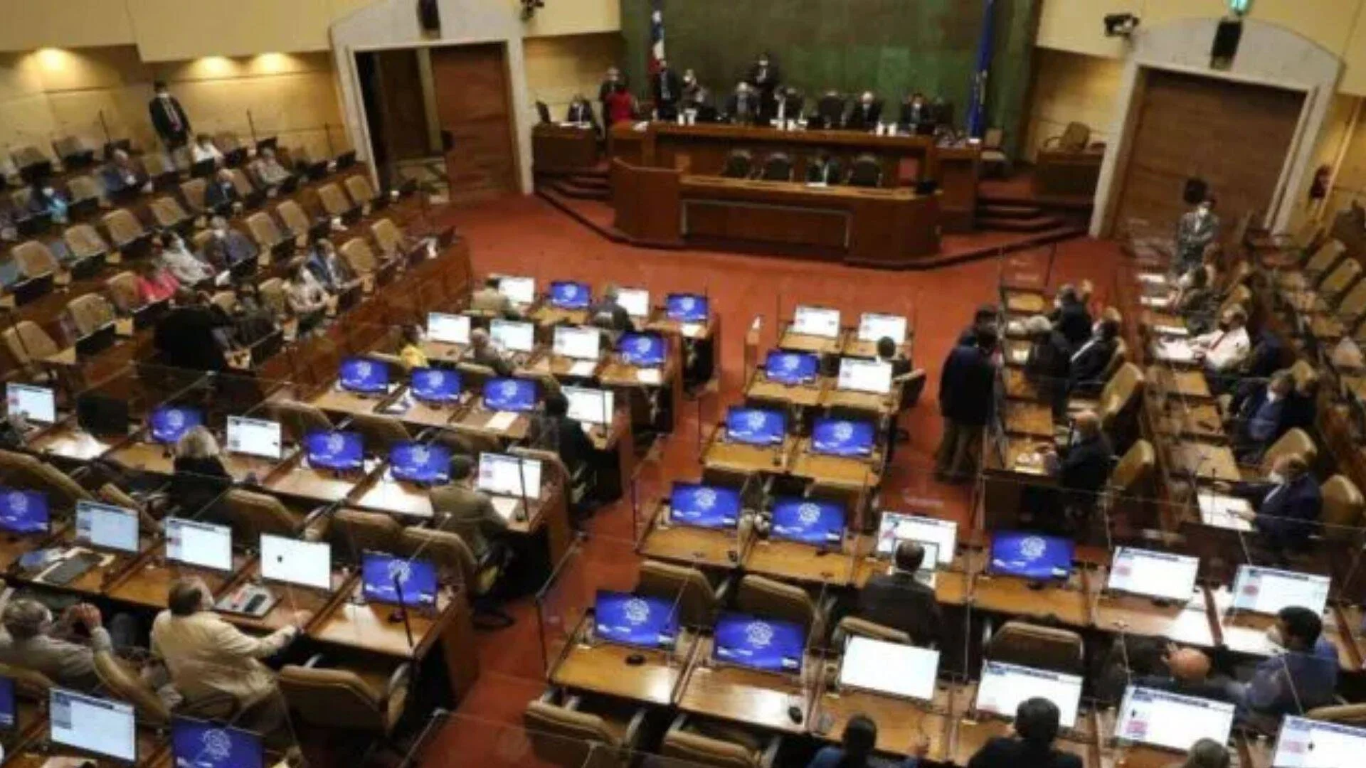 Vista aérea del hemiciclo de la Cámara de Diputados de Chile durante una sesión plenaria con parlamentarios en sus escaños.