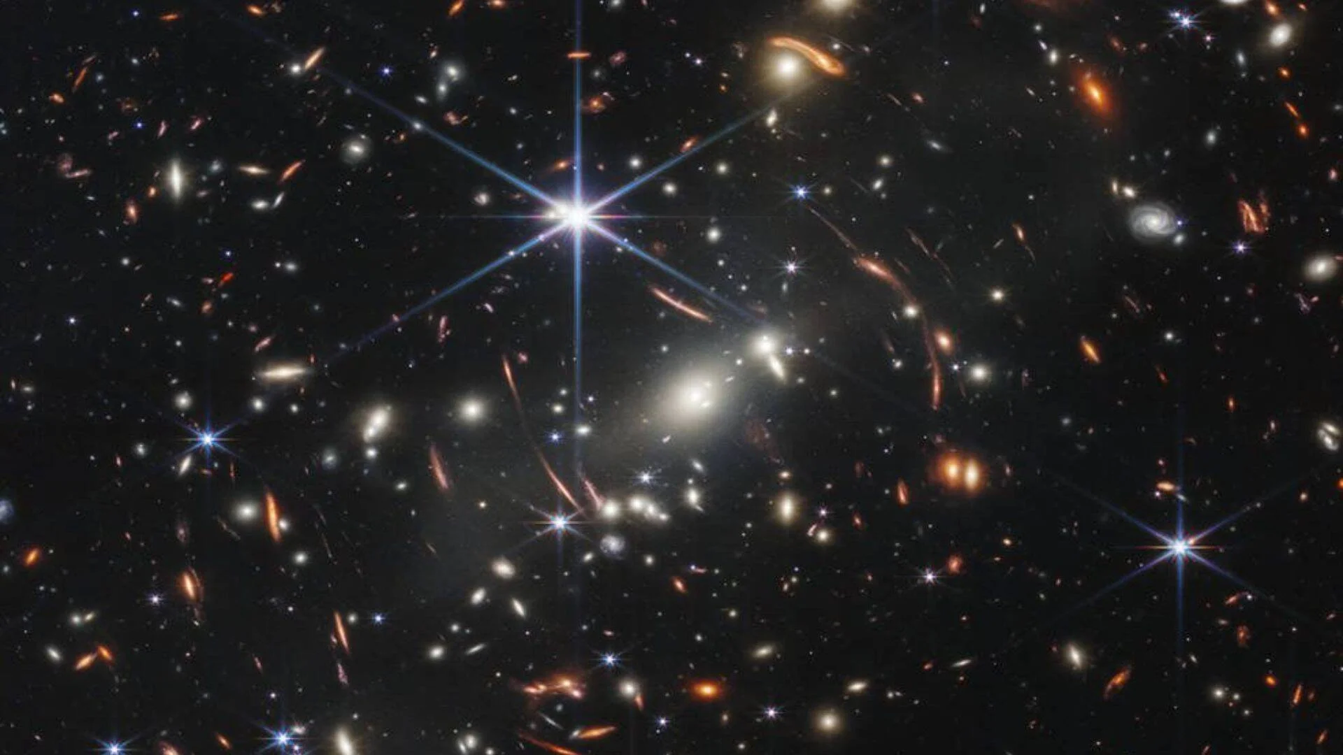 Campo profundo del universo captado por telescopio espacial, con miles de galaxias distantes y lentes gravitacionales sobre fondo negro.