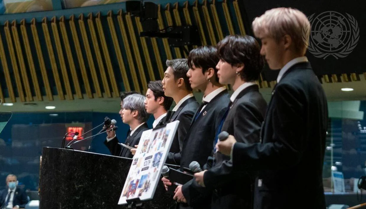 Varios jóvenes vestidos de traje negro hablan en el podio de la Asamblea General de las Naciones Unidas.