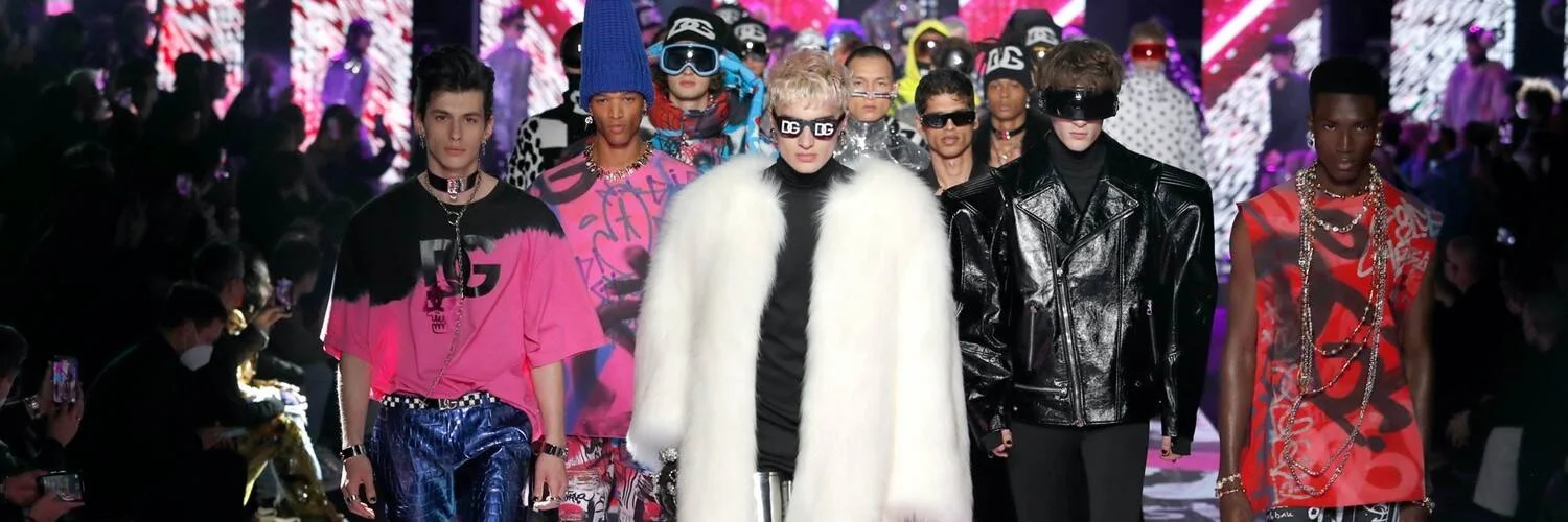 Grupo de modelos masculinos desfilan con prendas coloridas y extravagantes de Dolce & Gabbana ante el público.