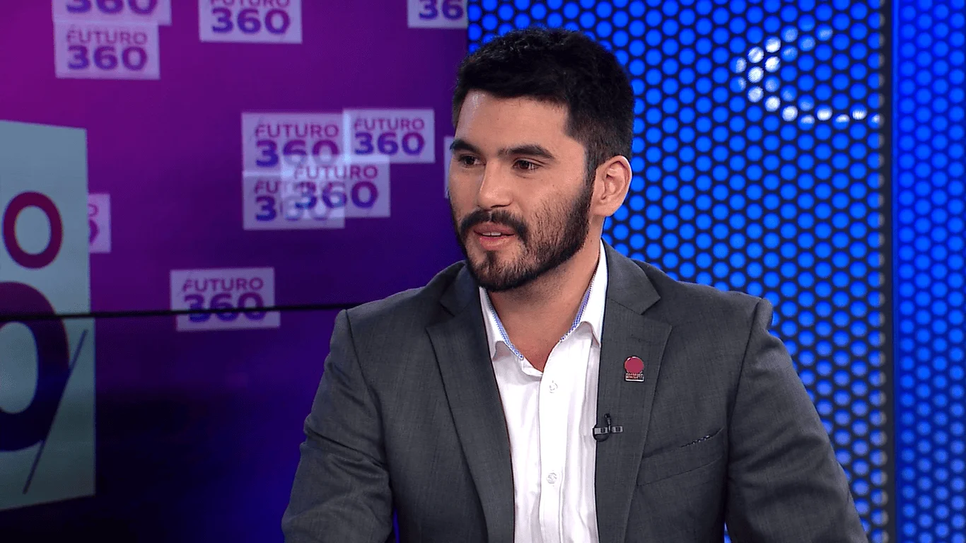 Hombre joven con traje gris y camisa blanca habla en el estudio del programa televisivo Futuro 360.