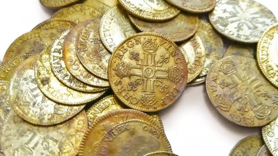 Grupo de monedas históricas con inscripciones latinas y símbolos reales, posiblemente de época colonial o medieval.