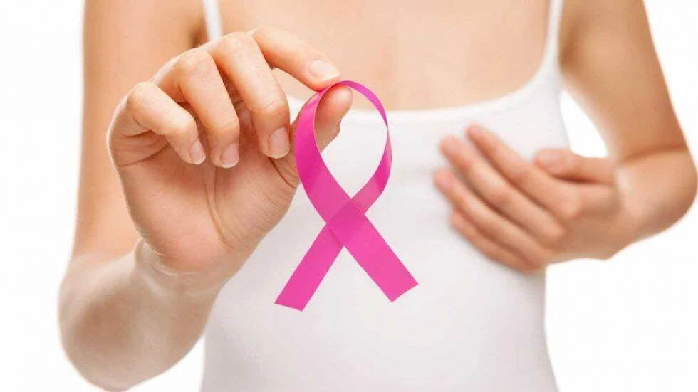 Mujer con remera blanca sostiene un lazo rosa, símbolo de concientización sobre el cáncer de mama.