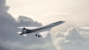 Renderizado del avión supersónico Overture volando entre nubes, con su diseño aerodinámico blanco y negro característico.