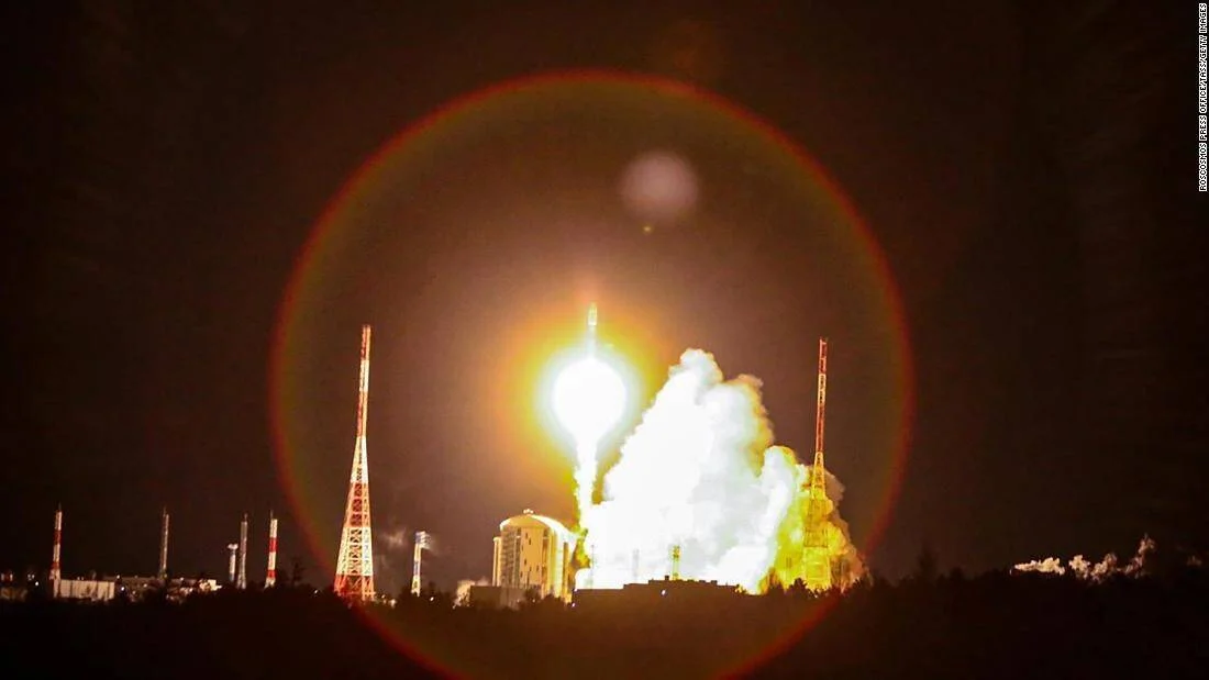 Cohete despega en plena noche desde una plataforma de lanzamiento, iluminando el cielo con una intensa llamarada y nubes de humo.