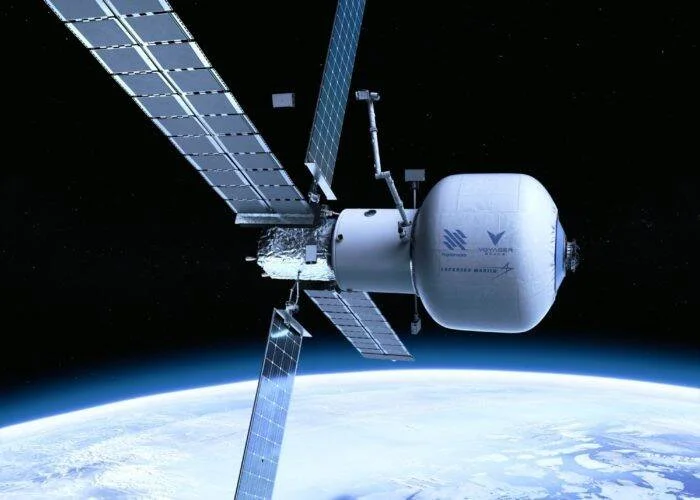 Ilustración de una estación espacial comercial con módulo hinchable y paneles solares orbitando la Tierra.
