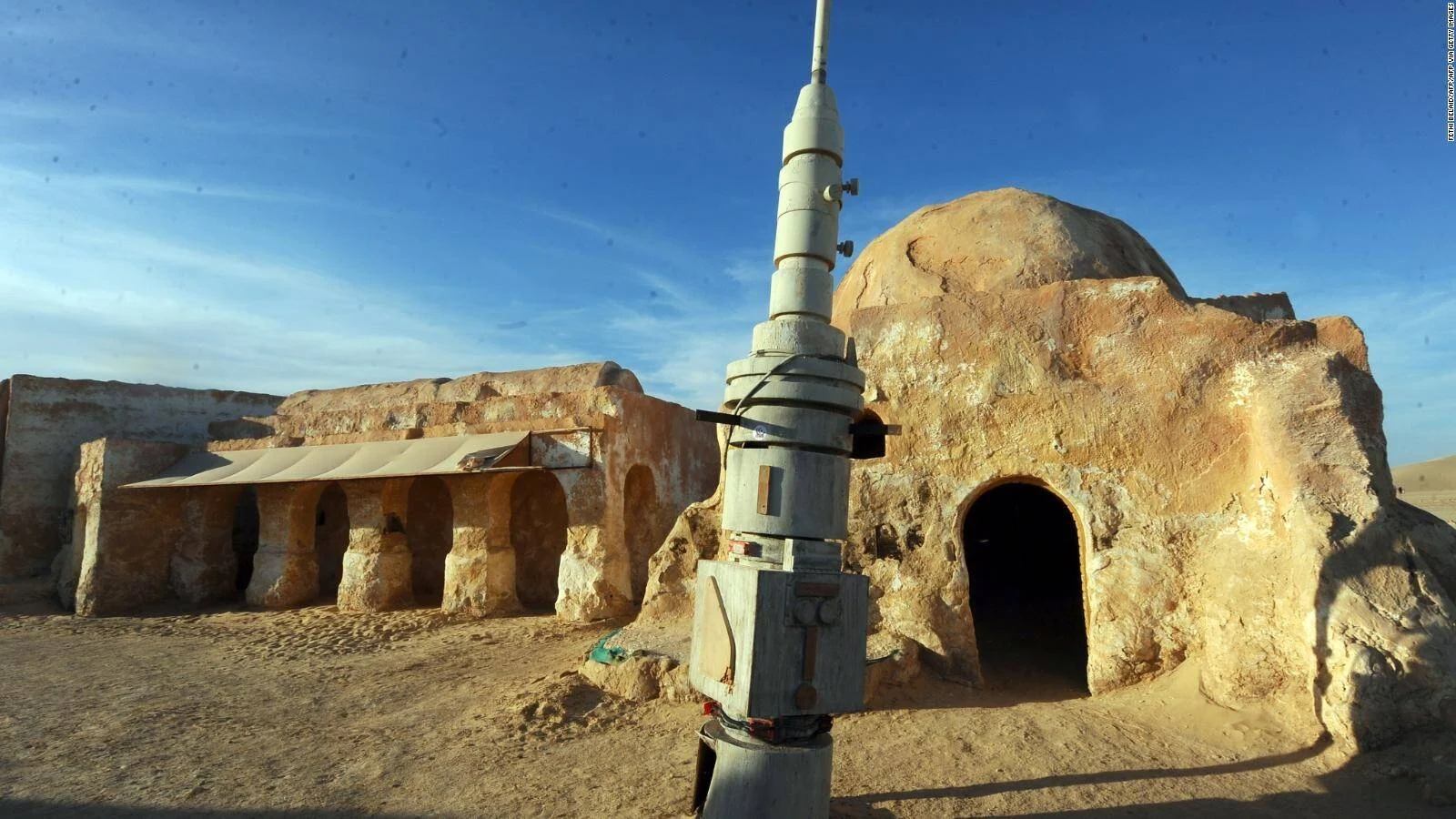 Construcciones de adobe con cúpulas y props futuristas del set de Star Wars en el desierto de Túnez bajo cielo azul.