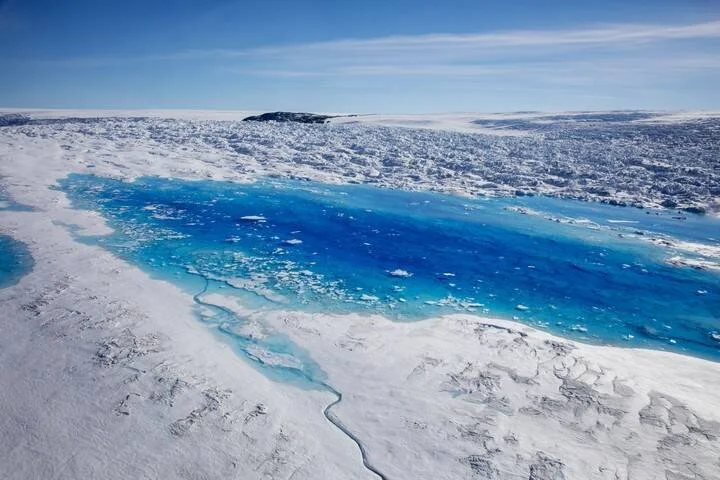 Lago de agua de deshielo de color azul intenso rodeado de hielo y nieve en una vasta capa glaciar polar.