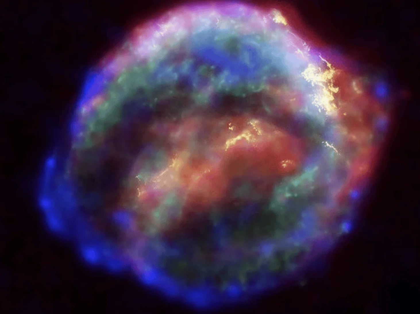 Nube esférica de gas y polvo cósmico en tonos azul, rojo y verde, resultado de la explosión de una supernova.