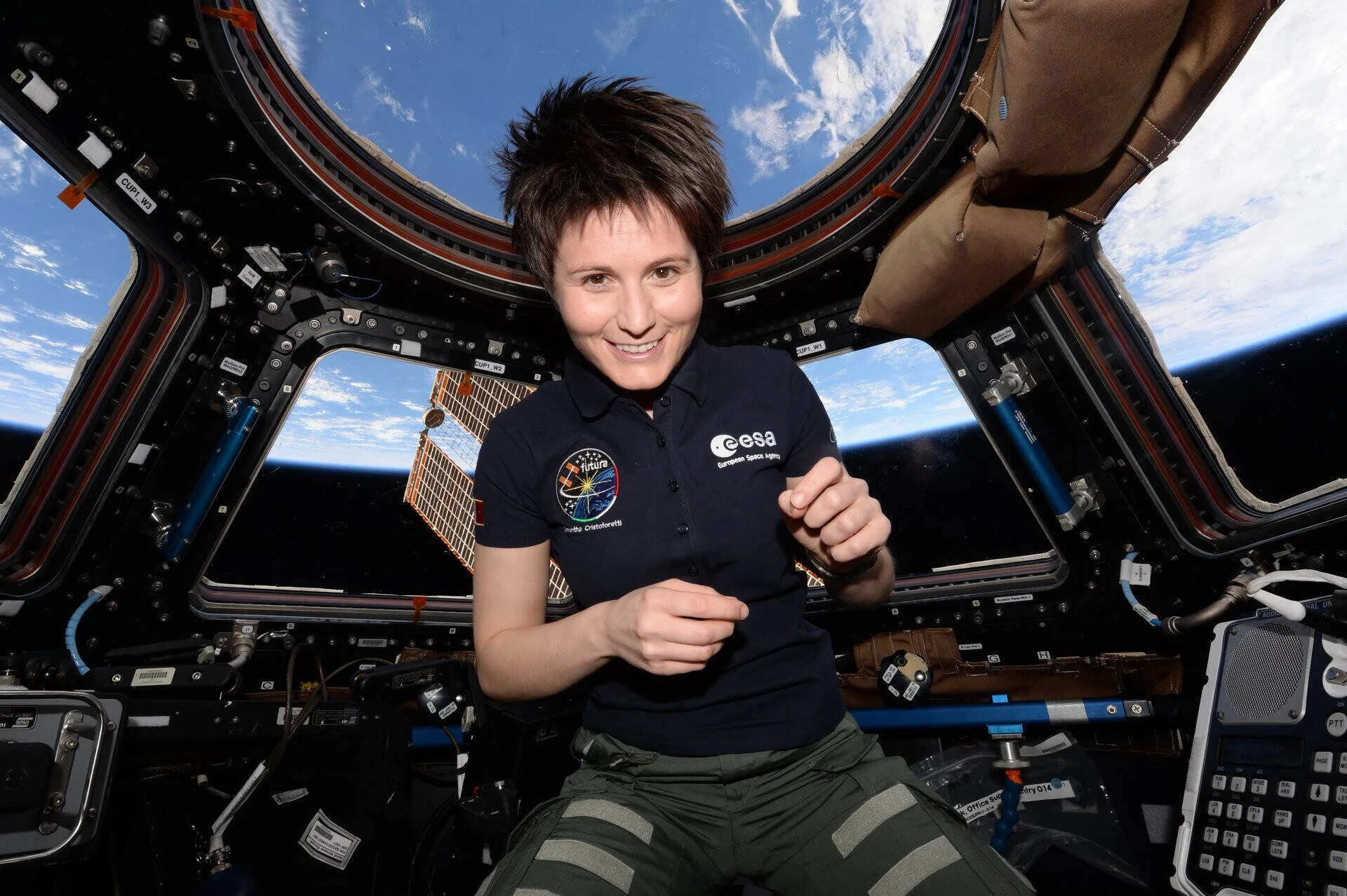 Astronauta de la ESA sonríe flotando en la cúpula de la ISS con la Tierra visible al fondo.