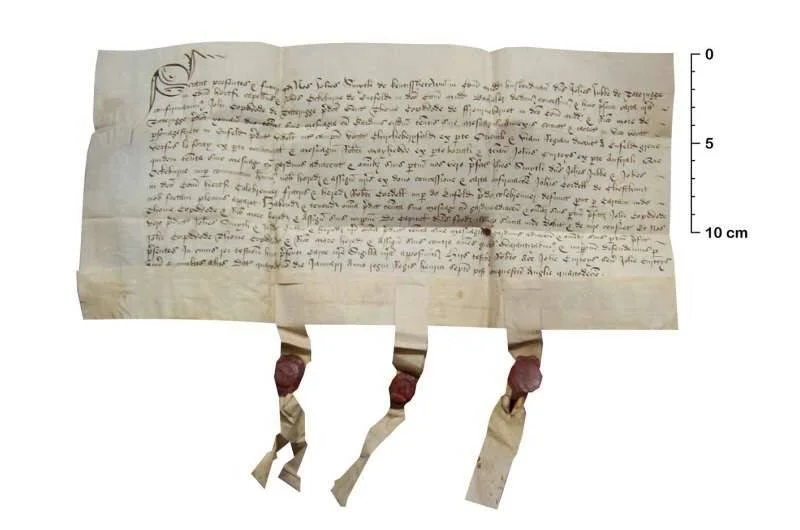 Pergamino medieval manuscrito en letra gótica con tres sellos de cera roja colgantes y escala de 10 cm.