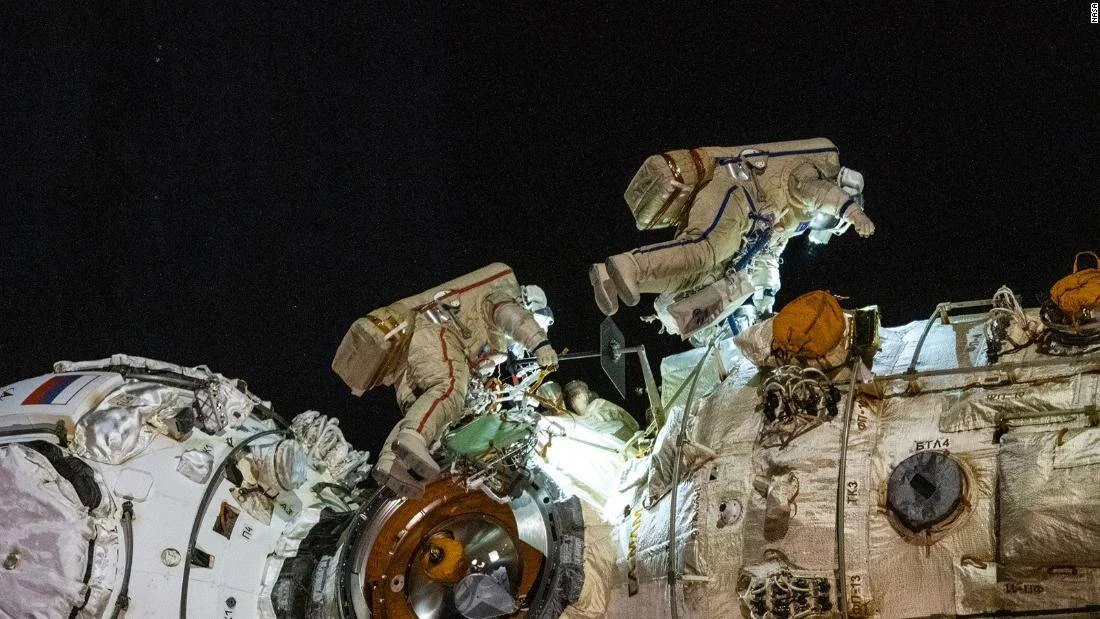 Dos cosmonautas con trajes espaciales rusos realizan una caminata espacial en el exterior de la Estación Espacial Internacional.