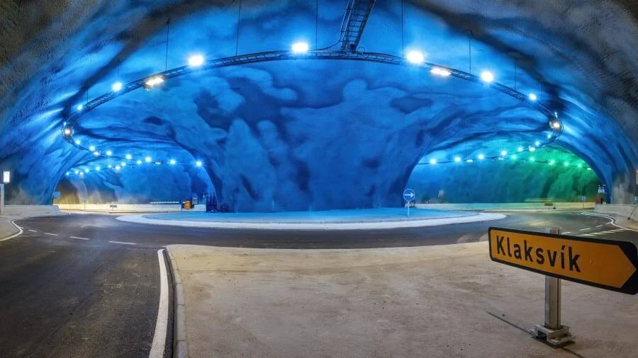 Rotonda iluminada con luces azules y verdes dentro de un túnel subterráneo con señal indicando Klaksvík.