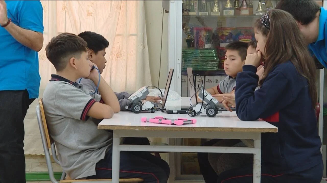 Grupo de estudiantes de primaria trabaja con robots LEGO sobre una mesa en clase de robótica educativa.