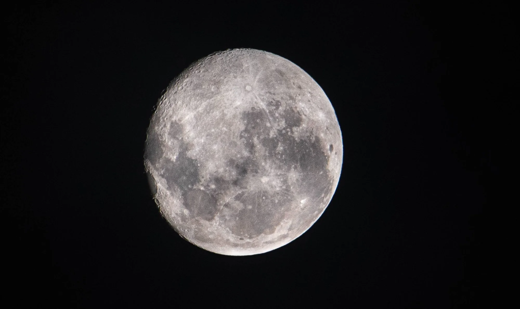 Vista cercana de la Luna casi llena con cráteres y mares lunares visibles sobre fondo negro.
