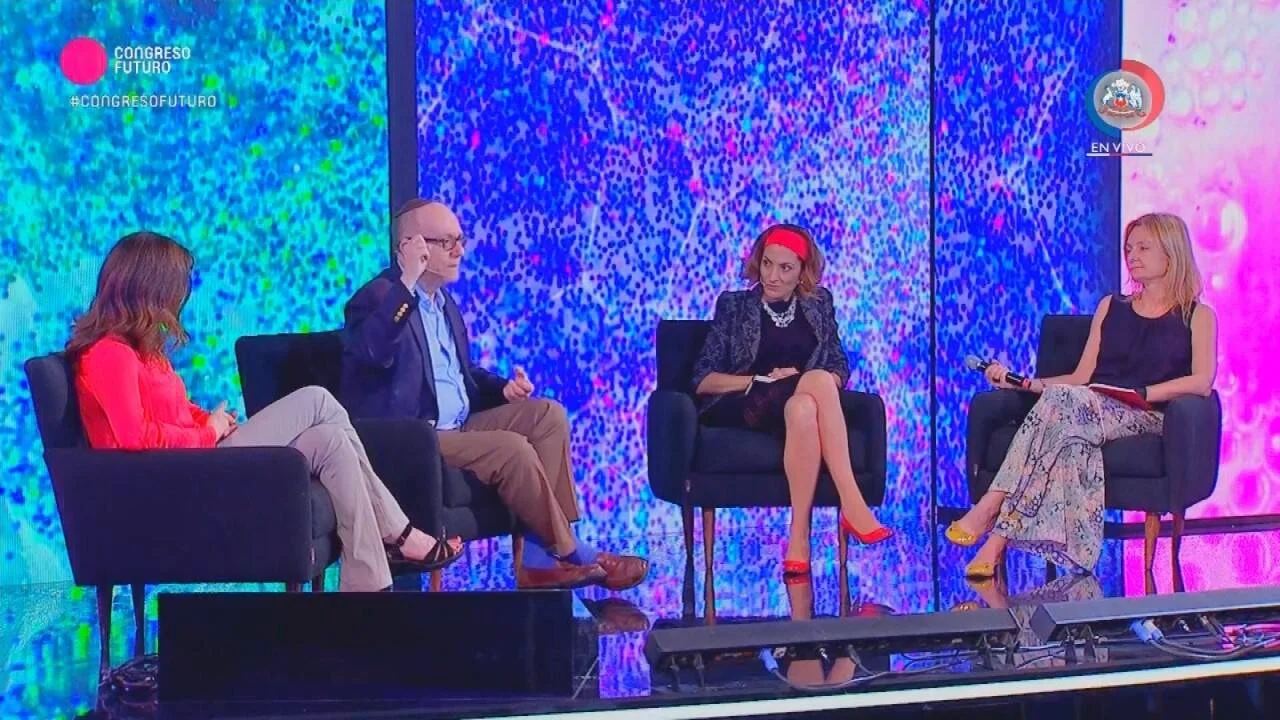 Cuatro panelistas sentados en sillones negros conversan en el escenario del Congreso Futuro, con pantallas LED coloridas de fondo.