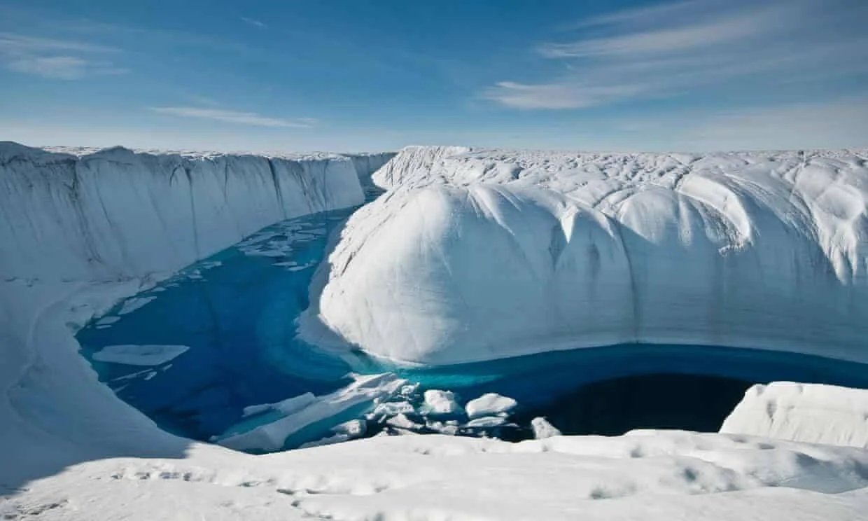 Canal de agua de deshielo de color azul intenso tallado entre paredes de hielo blanco en una capa de hielo polar.
