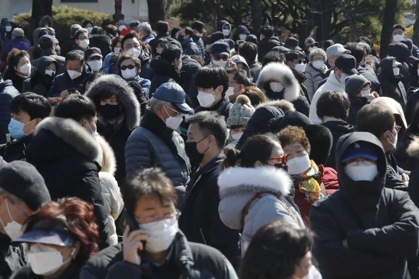 Gran multitud de personas con mascarillas de protección reunidas al aire libre en invierno.