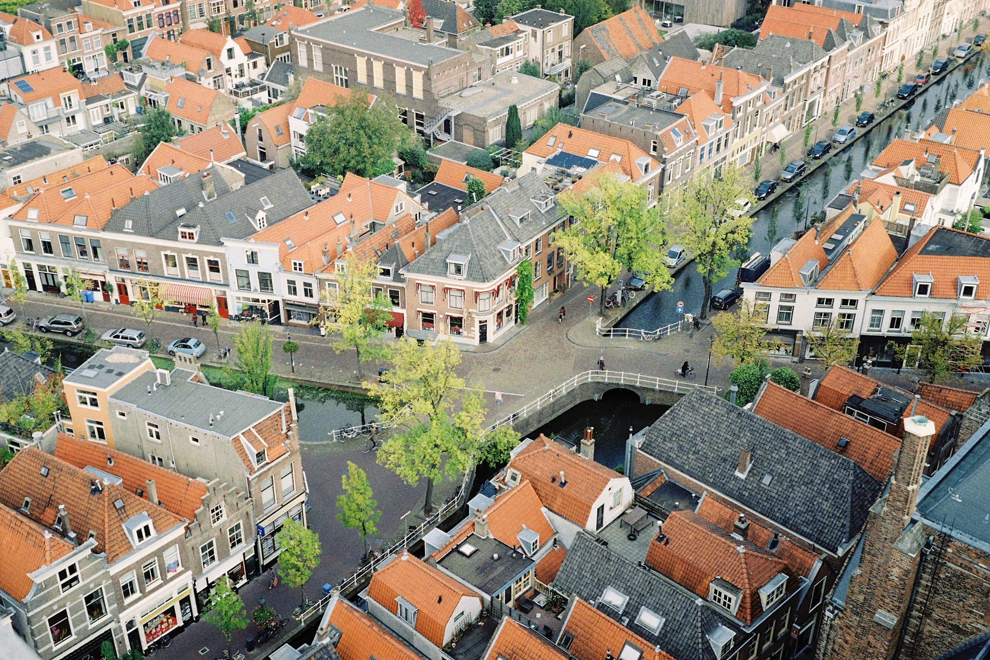 Vista aérea de una ciudad holandesa con canales, puentes, tejados naranjas y edificios históricos densamente agrupados.