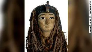 Máscara funeraria del antiguo Egipto con decoración polícroma y peluca trenzada oscura.