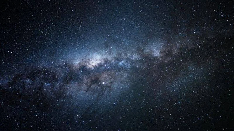 Vista panorámica de la Vía Láctea con miles de estrellas y nubes de polvo cósmico sobre un cielo nocturno oscuro.