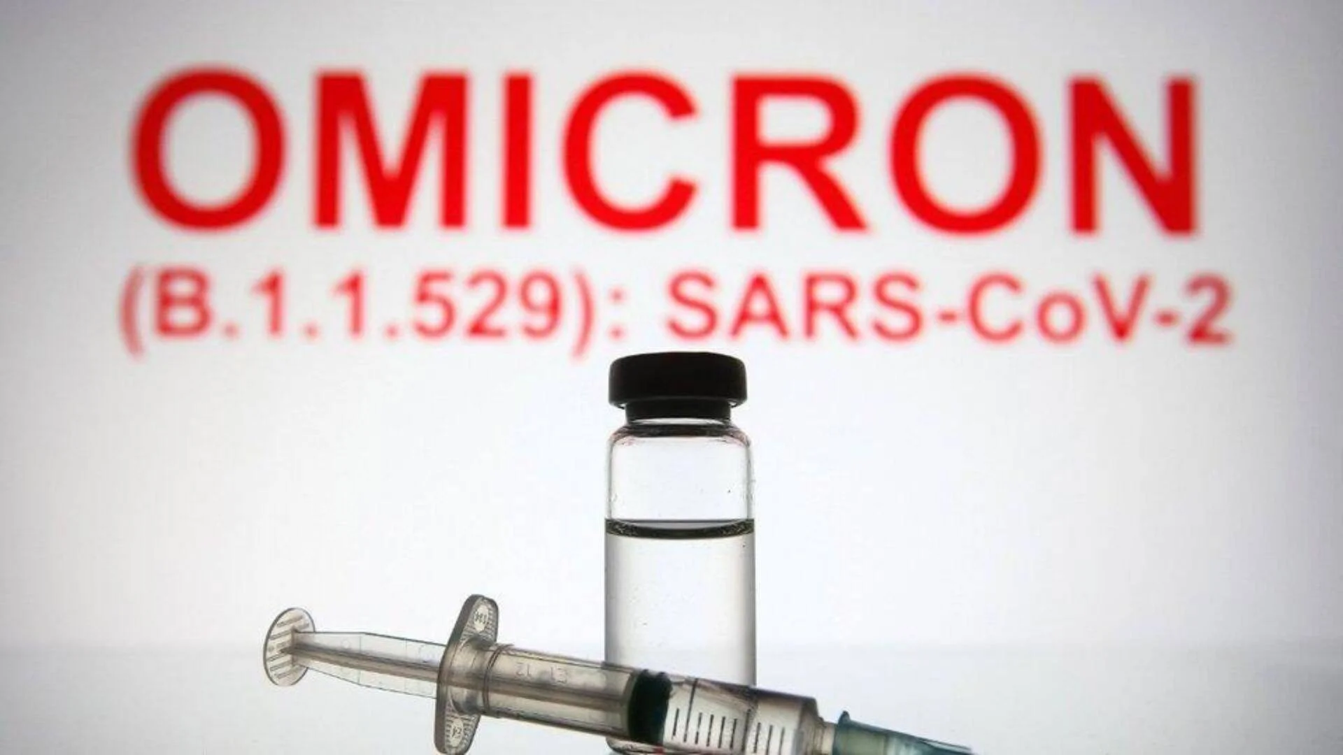 Frasco de vacuna y jeringa frente a un letrero rojo con el texto 'Omicron (B.1.1.529): SARS-CoV-2'.